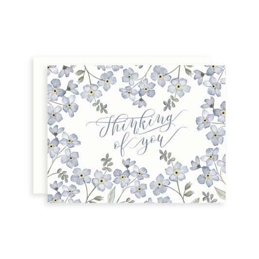 Greeting card with watercolor forget-me-not wildflowers and 'Thinking of you' text on a white background