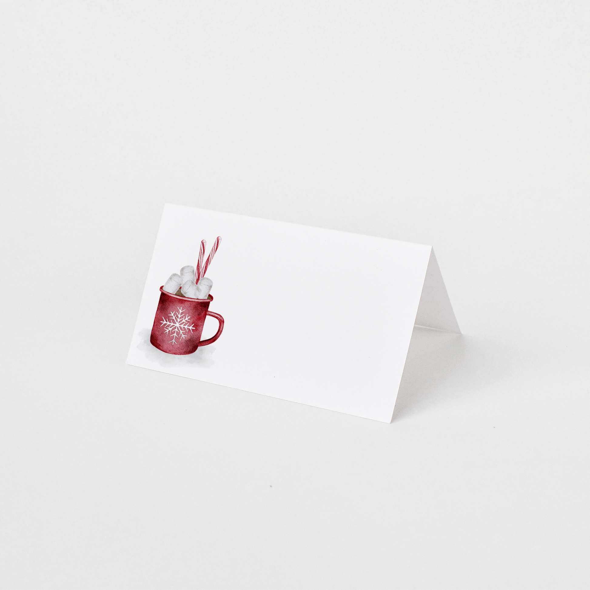 Folded place card with a red mug of hot cocoa, marshmallows and candy canes, on a white background