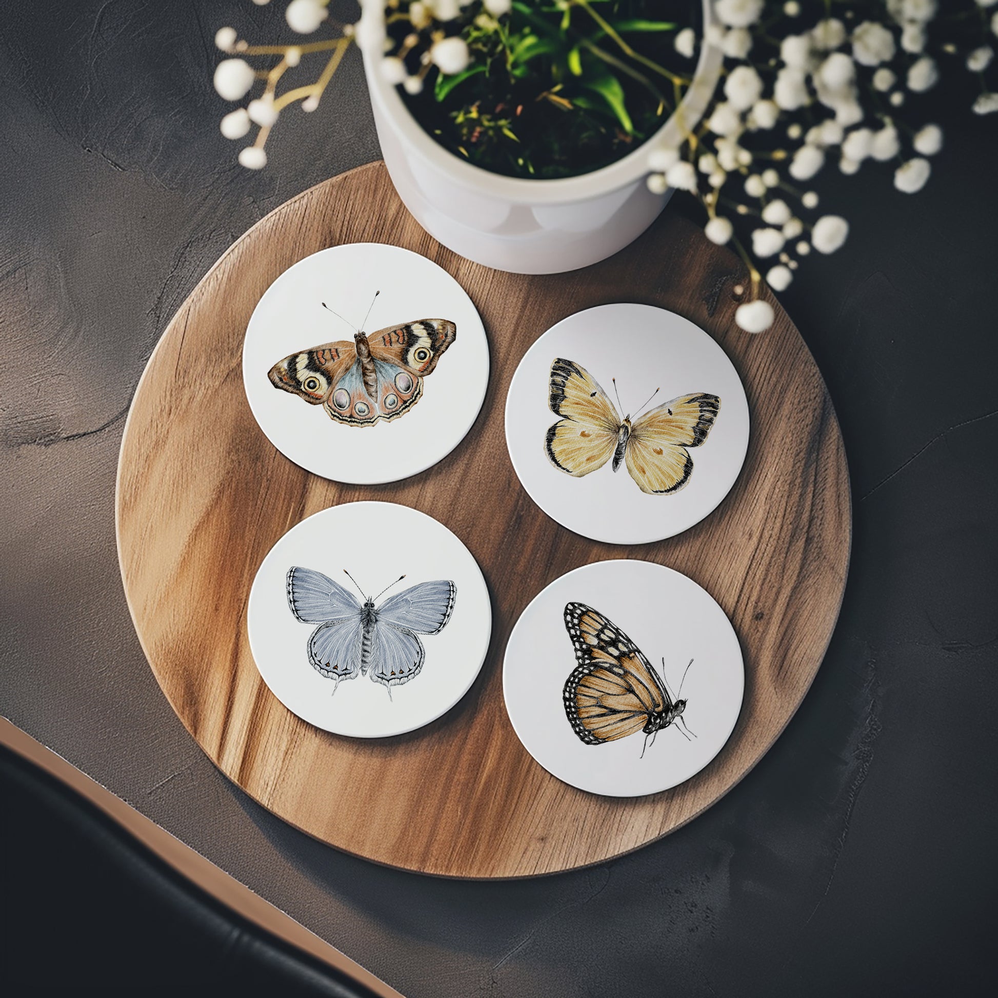 Set of 4 round stone ceramic coasters featuring a watercolor butterfly illustration on a white background