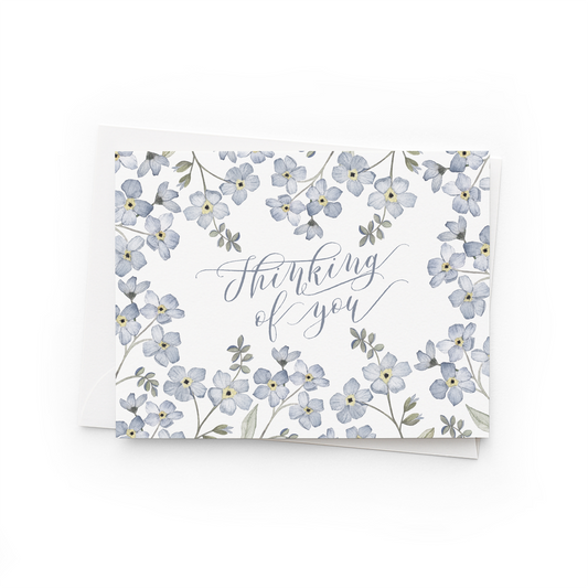 Greeting card with forget me not floral design and 'Thinking of you' text on a white background